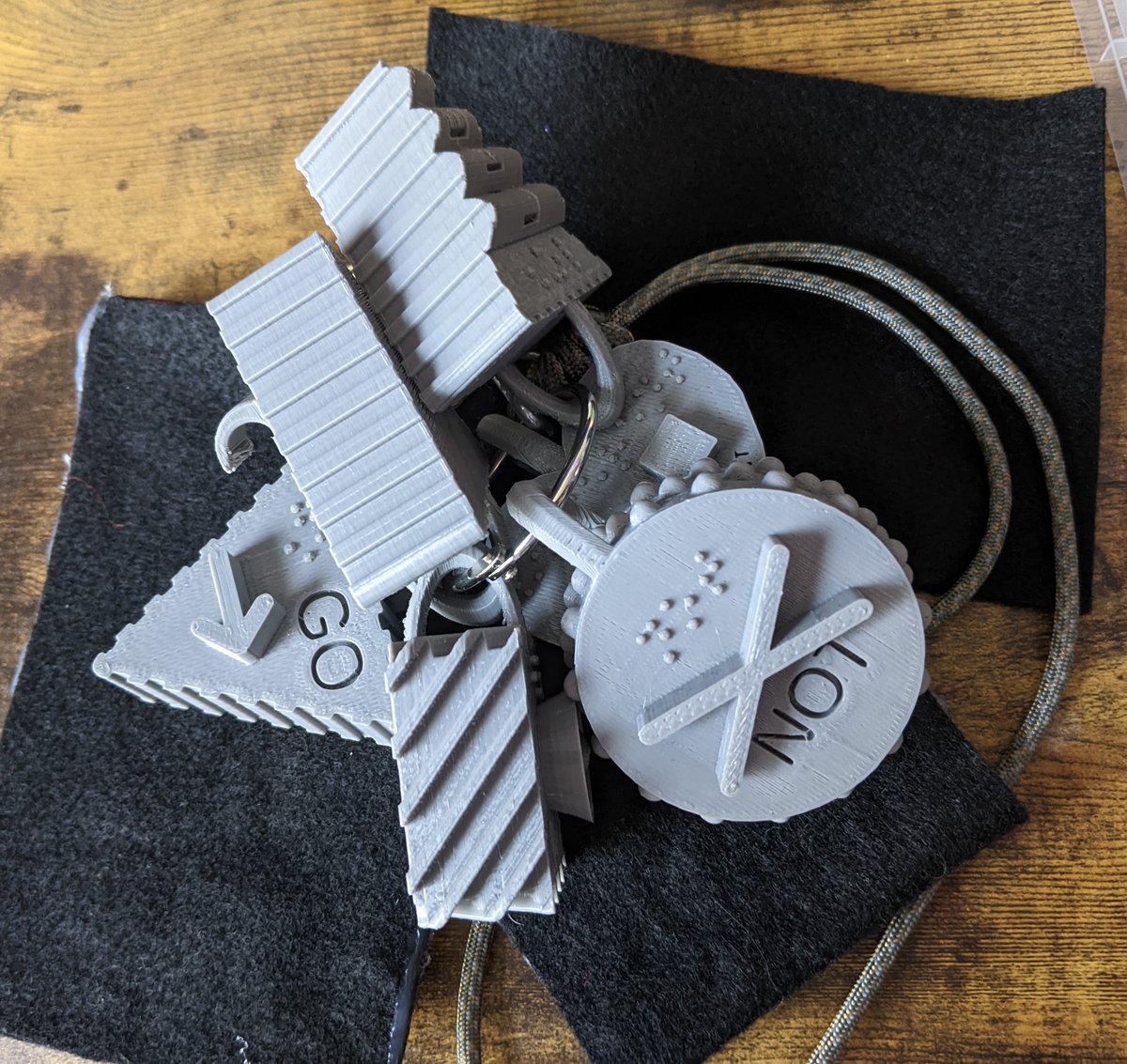talkaactome's tweet photo. Anyone ever use #projectcore #3dprinted #AAC symbols w/ ambulatory student w/ VI & difficulty pointing? This is a prototype where I hung them on a lanyard and used black felt rectangles for contrast but it's so awkward. How to mount/transport? https://t.co/4Gcb8u8ZiQ