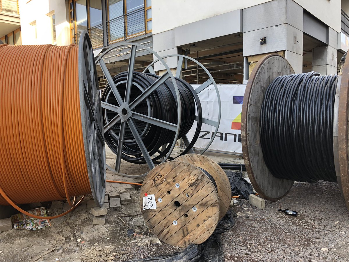 Drei riesige und eine kleine Kabeltrommel vor einem zerstörten Laden.