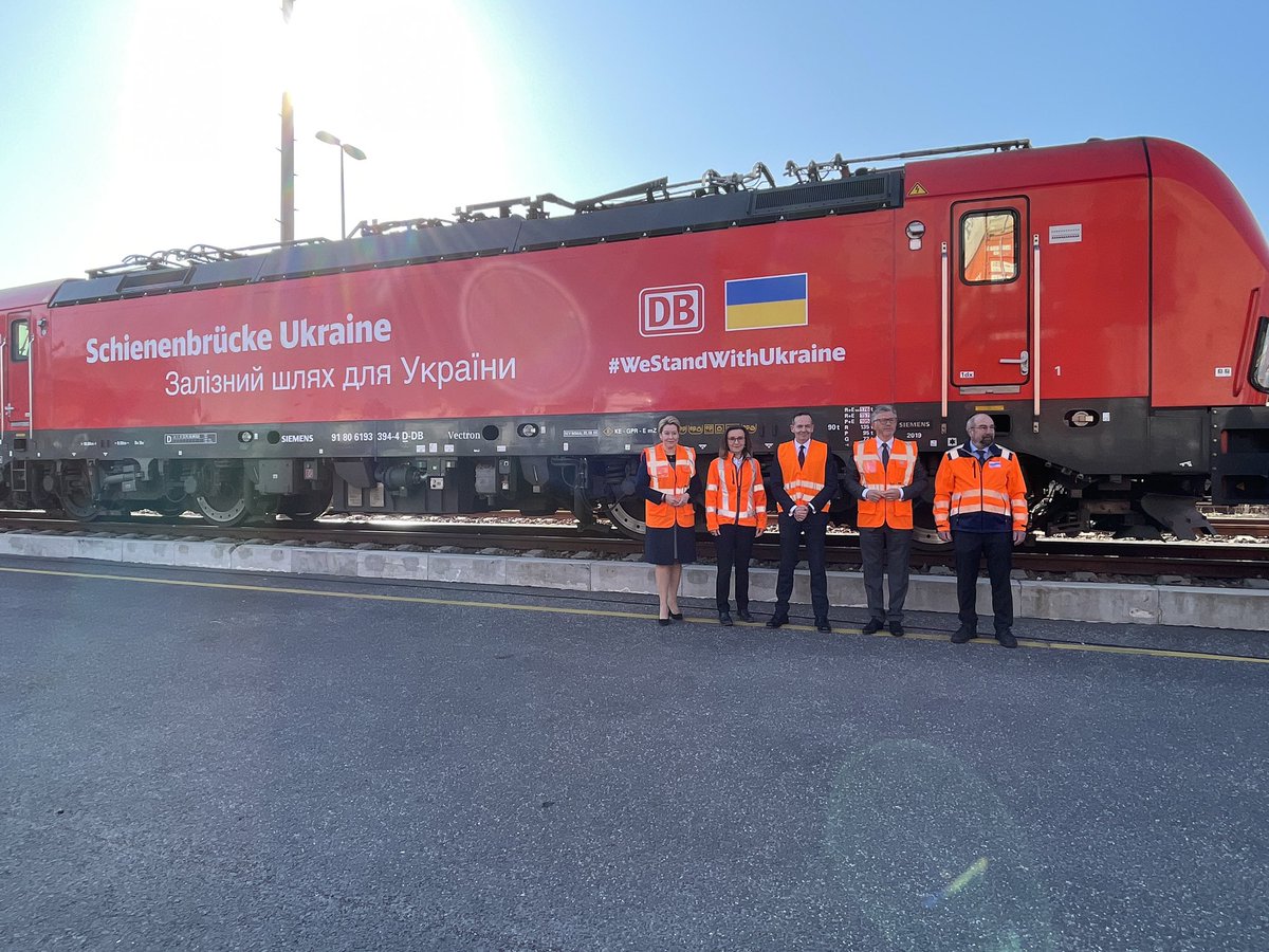 Die Regierende Bürgermeisterin FranziskaGiffey, der ukrainische Botschafter Andrij Melnyk, Bundesverkehrsminister Volker Wissing und DB-Vorständin Sigrid Nikutta stehen vor einem Zug, der Hilfsgüter in die Ukraine transportiert. Auf der Lok ist „Schienenbrücke Ukraine“ sowie „#WeStandWithUkraine“ und die ukrainische Flagge zu sehen.