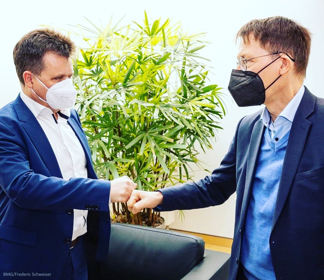 Lauterbach und Dusel begrüßen sich, ihre Fäuste berühren sich (statt Handschlag).