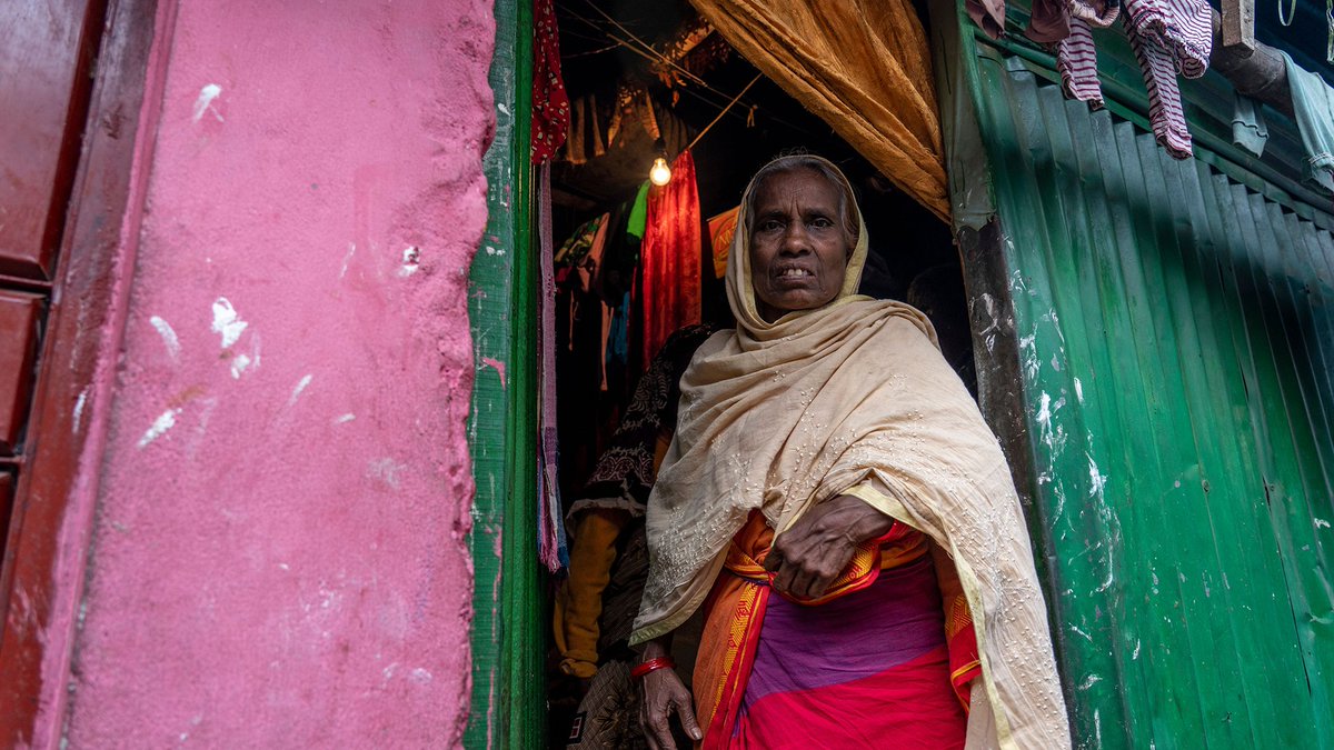 Hasina stands in the doorway to her home.