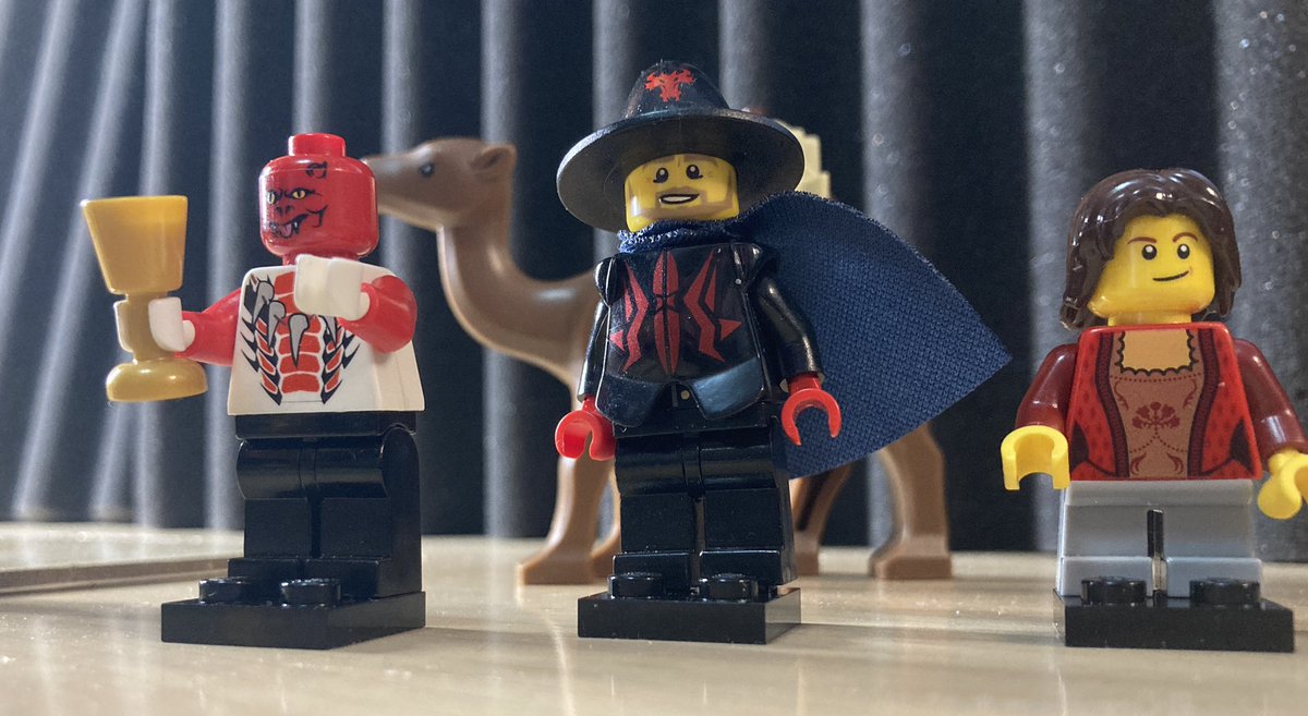 A tiefling, a wizard, and a halfling walk by a camel.