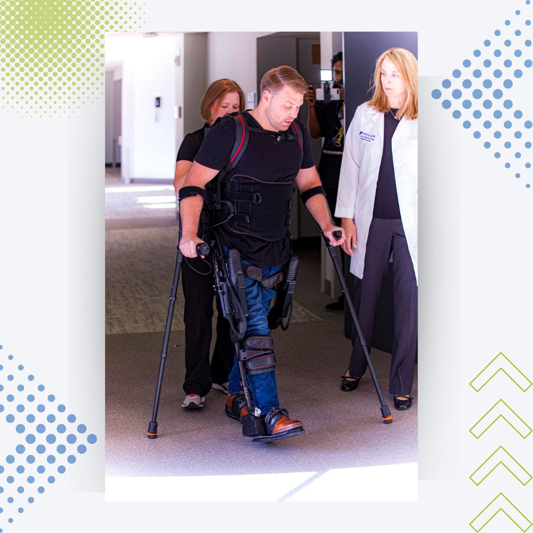 A man is using the robotic exoskeleton while holding onto canes in both hands. A physical therapist is seen behind him and Dr. Karen Nolan from Kessler Foundation is to his side. They are walking down a hallway. 