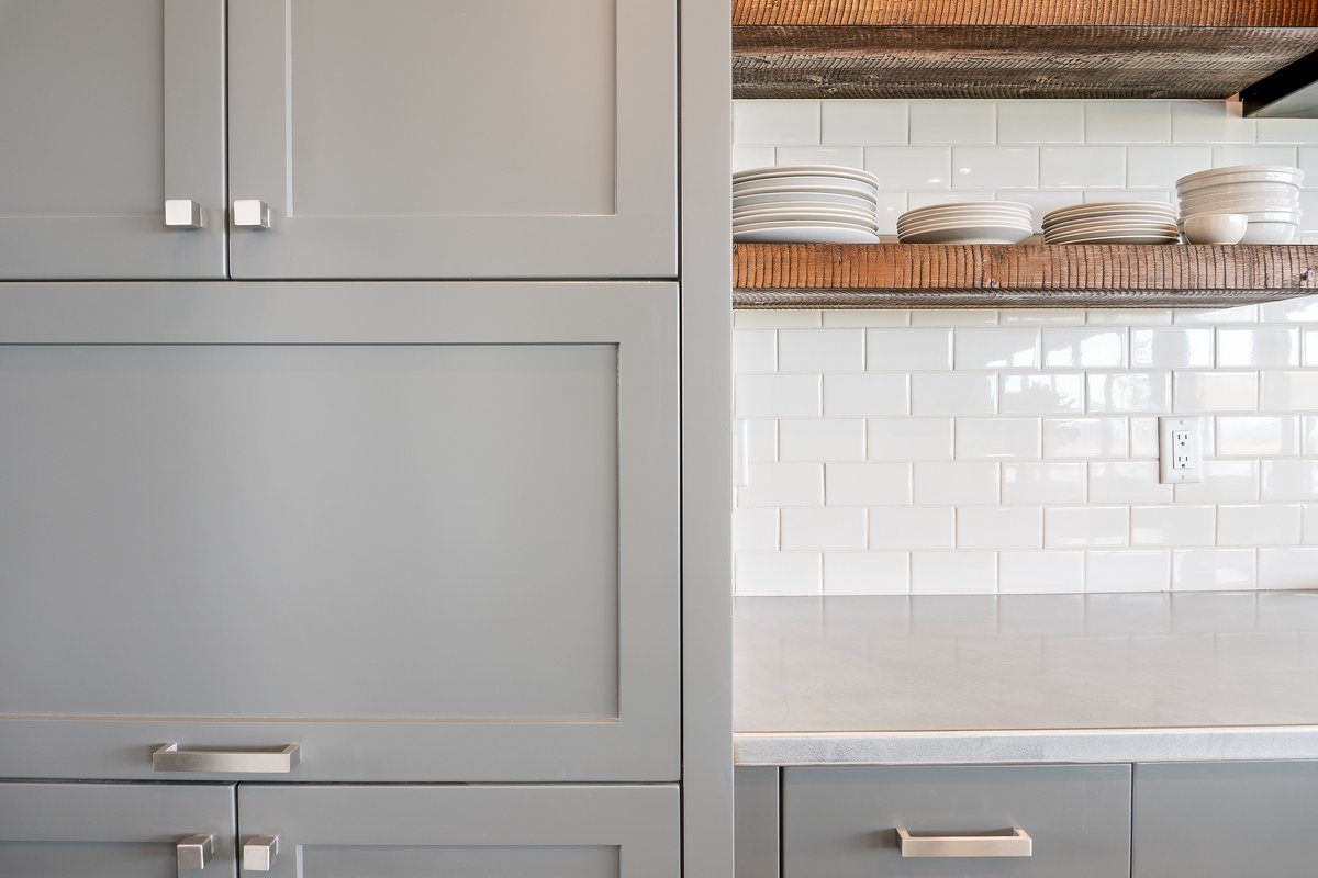 Grey &amp; Wood looks beautiful in this shaker and slab profile design. We love the hood cover, the textured backsplash tile, and the showpiece floating shelves. The surfaces are a carefully paired concrete natural colour quartz that bring the look together.