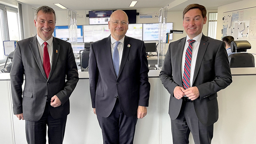 Der Parlamentarische Staatssekretär im BMI, Johann Saathoff, BSI-Präsident Arne Schönbohm und der innenpolitische Sprecher der SPD-Bundestagsfraktion, Sebastian Hartmann, stehen vor Monitoren im BSI-Lagezentrum in Bonn.