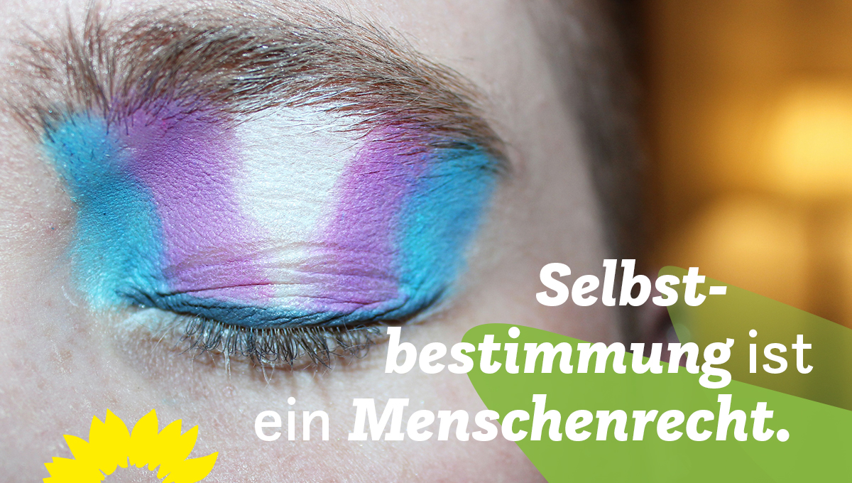 Auf dem Bild ist ein geschlossenes Auge zu sehen, dessen Lid mit den Farben der Transgender-Flagge geschminkt ist. In der rechten unteren Ecke steht auf grünen Blättern: Selbstbestimmung ist ein Menschenrecht.