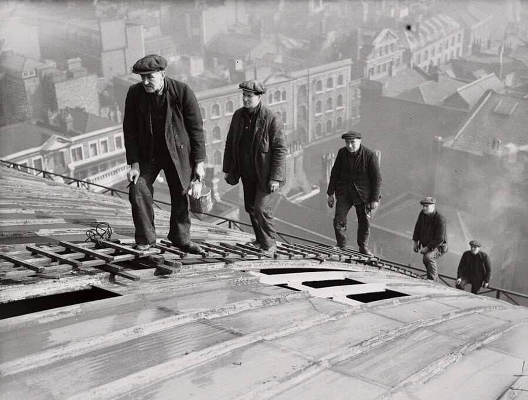 It’s early morning on 11 March 1936 ~ stoic workmen in suits and caps arrive to paint & clean the roof of London’s Cannon Street Railway Station. The misty city lies far below (Roofers, Harry Todd)