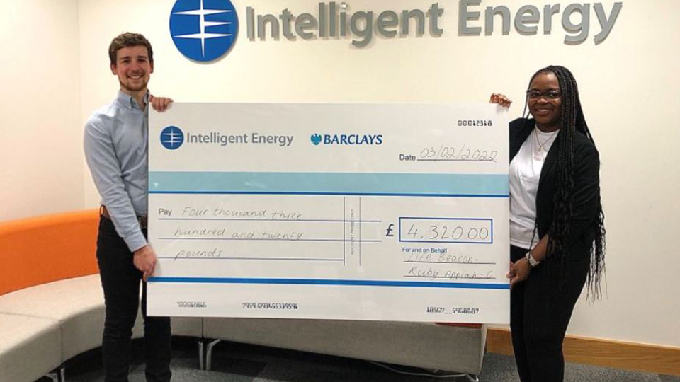 Two people hold a giant cheque for £4,320.