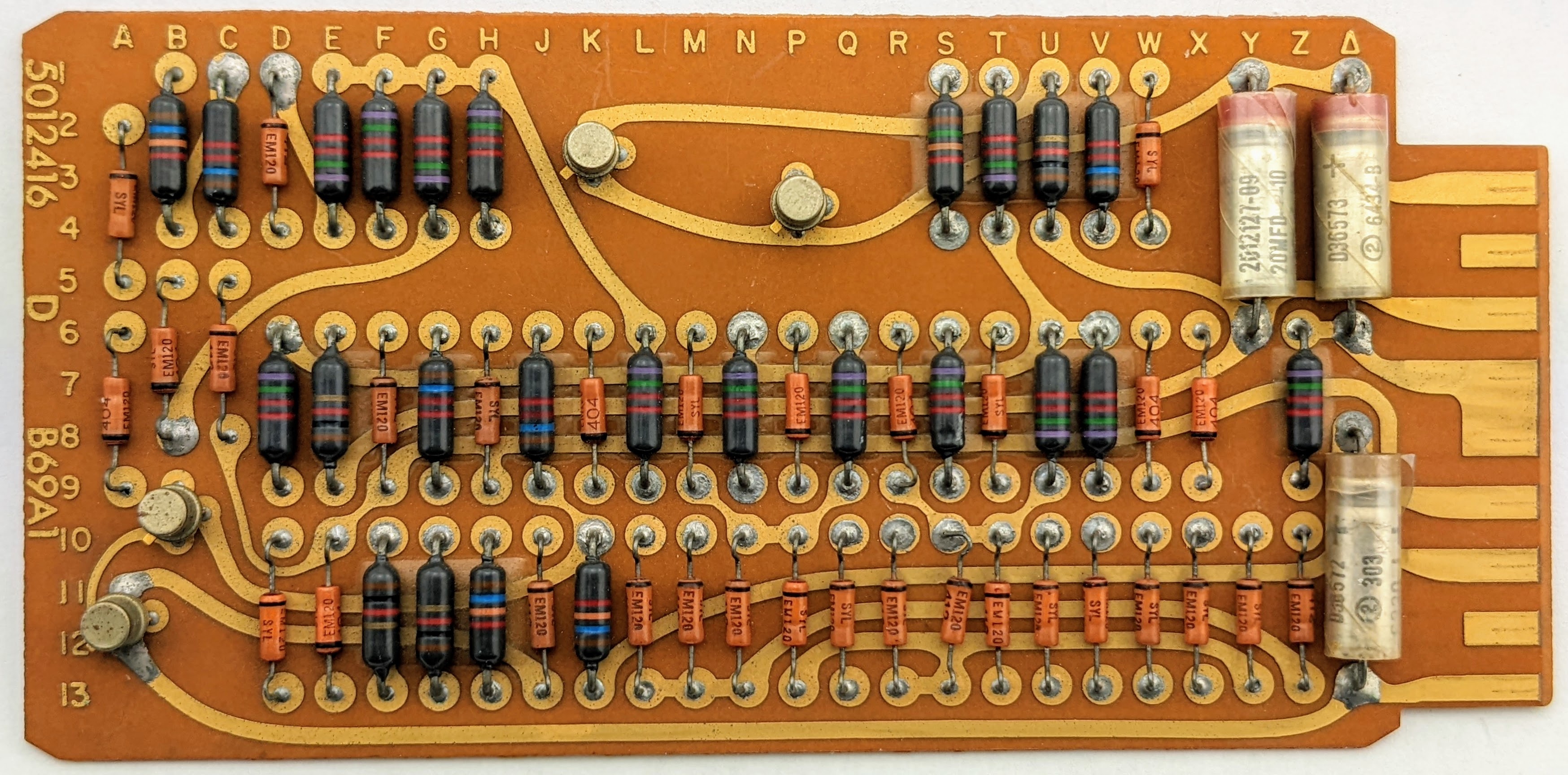 A rectangular circuit board, a bit bigger than a playing card. It is covered with resistors and diodes, along with a few transistors and capacitors. It has a chunky 8-contact edge connector at the right.
