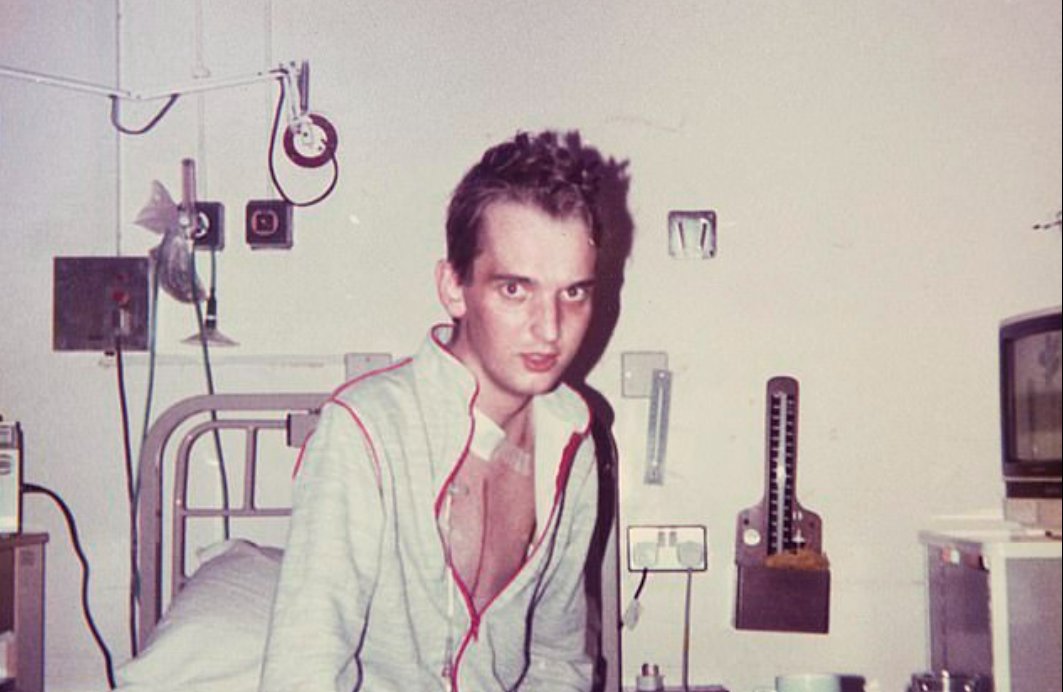 An old photo of Richard, wearing a jacket half unzipped, showing a scar down his chest.