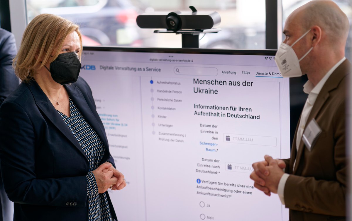 Nancy Faeser spricht mit einem Mitglied des Entwicklerteams von Germany4Ukraine.de Im Hintergrund ist ein Bildschirm zu sehen, auf dem der Online-Antrag für den Aufenthaltstitel zu sehen ist. 