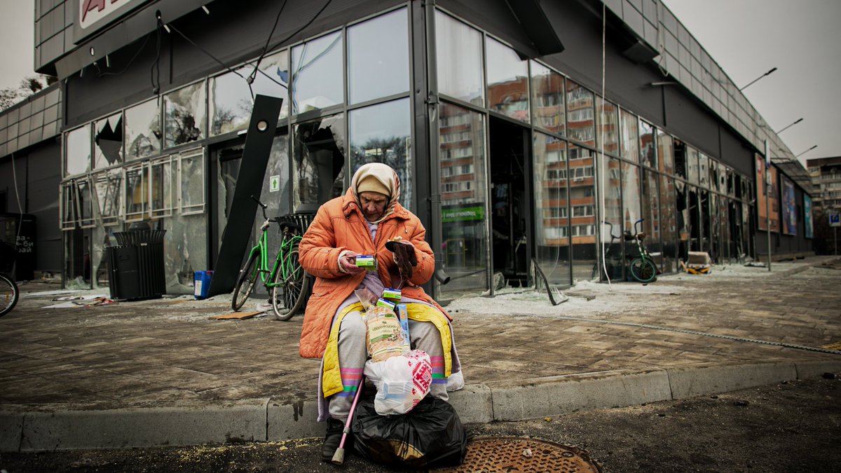 Cette dame venait de recevoir quelques denrées alimentaires de la part des volontaires présents à Boutcha ce matin. Derrière elle, un centre commercial totalement soufflé par une explosion.