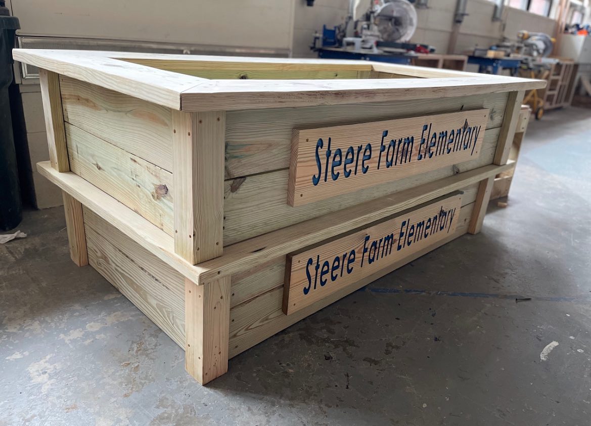 Great work by our @BHSCTECM students! A little bit more sanding so students at SFE don’t get any splinters &amp; these raised garden beds will be out for delivery! Also a shoutout to <a href="/bronco_steam/">STEAM@BurrillvilleSchools</a>  for their CNC work on the signs!  @DrLyonsSFE <a href="/BHSBroncos/">Burrillville HS Broncos</a> <a href="/CTE_RI/">CTE Rhode Island</a>