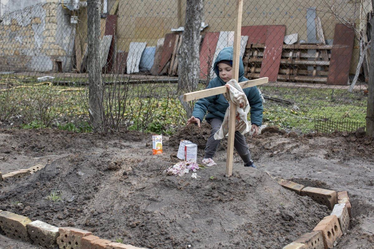 DMokryk's tweet photo. Yes, it's Bucha again. A survivor boy brings canned food to his mother's fresh grave.

#BuchaMassacre https://t.co/F18Bv8Ccfa