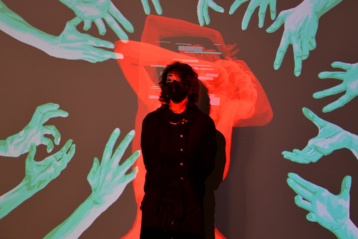Artist Cassandra St. Godard in front her digital art work showing a red portrait surrounded by blue hands depicting anxiety and trauma.