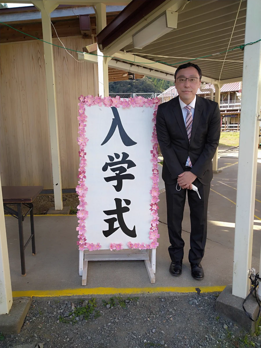 娘に写真を拒否された父。娘の入学式の看板の前で一人写真。
