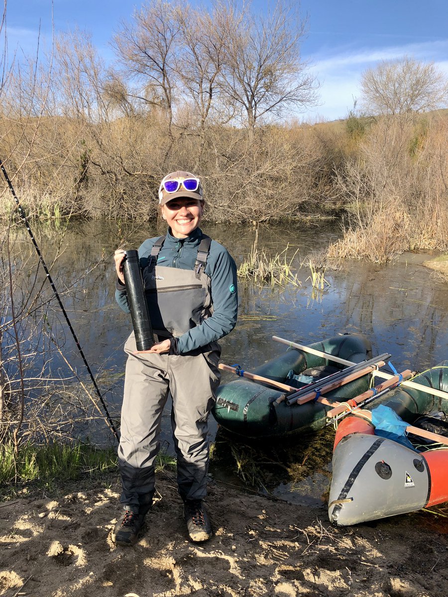Me holding a sediment core by a beaver pond wearing a jacket and waders