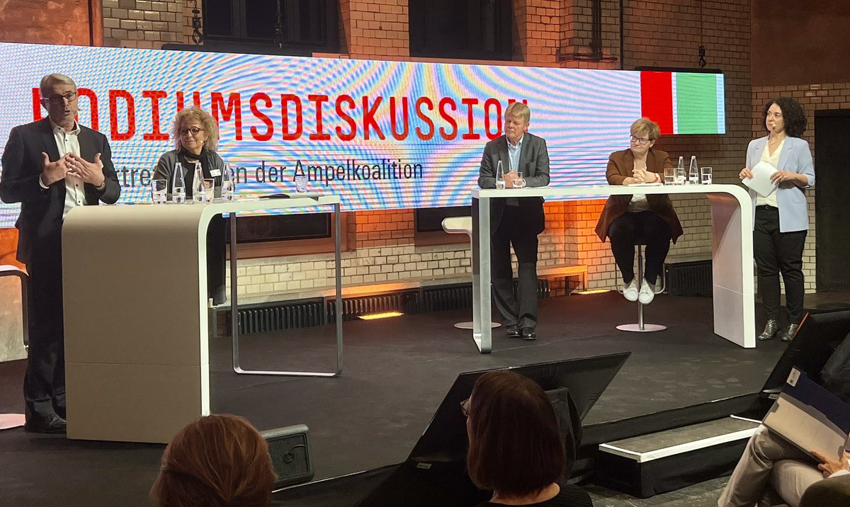 2 Männer & 3 Frauen stehen an Rednerpult auf einer Bühne