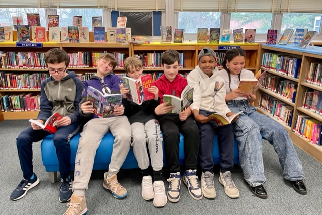 Mrs. McCarthy and Mrs. Dickinson's 7th grade ELA class reading in the library at ENMS during National Library Week 2022📚