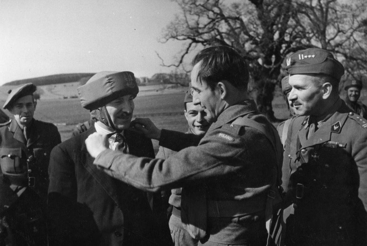 WW2Today's tweet image. 20th April 1942

Second Lt of the 1st Polish Independent Parachute Brigade adjusting a bungee helmet (paratrooper&apos;s training helmet) on Clement Attlee&apos;s head during his visit to the Brigade. Cupar Colonel Stanisław Sosabowski, the Commander of the Brigade, is on the right.

#OTD