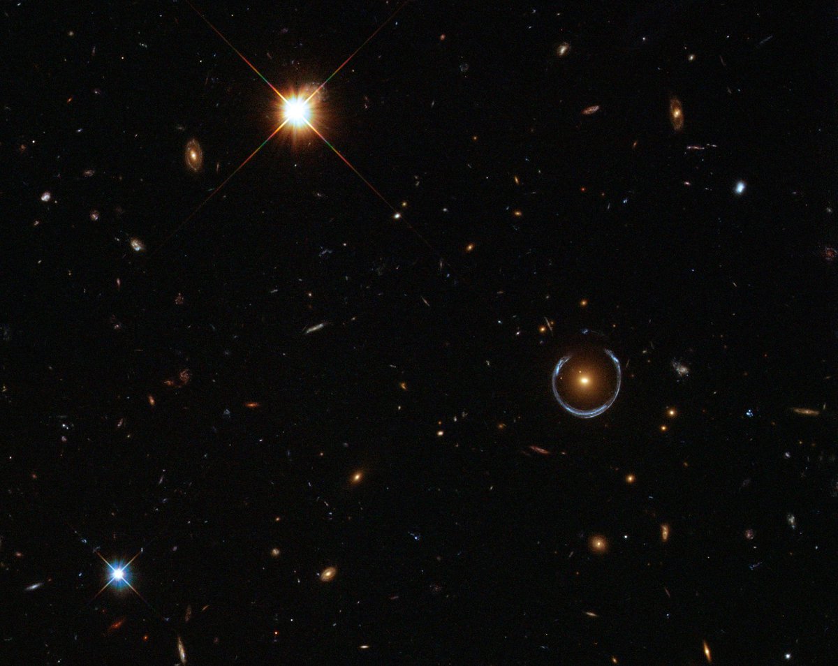Even though the red galaxy near the center of this image looks tiny, it’s actually 10 times the mass of the Milky Way. Its gravity allows it to bend the light of the galaxy behind into a horseshoe shape. 

Credit: ESA/Hubble &amp; NASA.