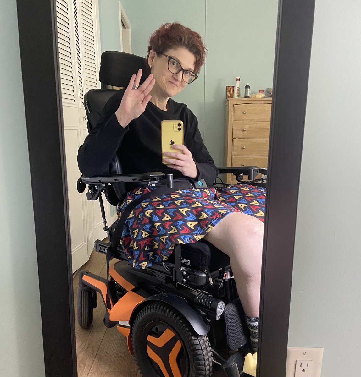 Photo of me in my orange power wheelchair wearing a skirt with Star Trek insignia