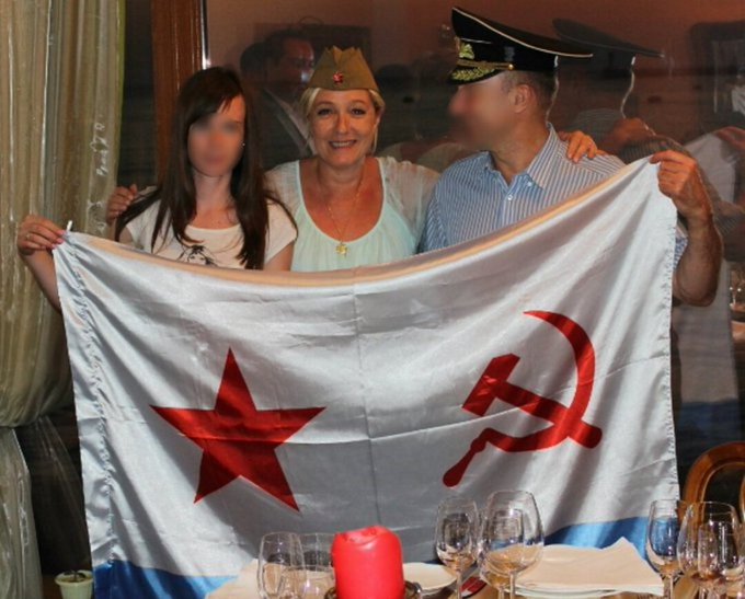Le Pen in Russia-occupied Crimea with the Soviet flag and wearing a Soviet hat.