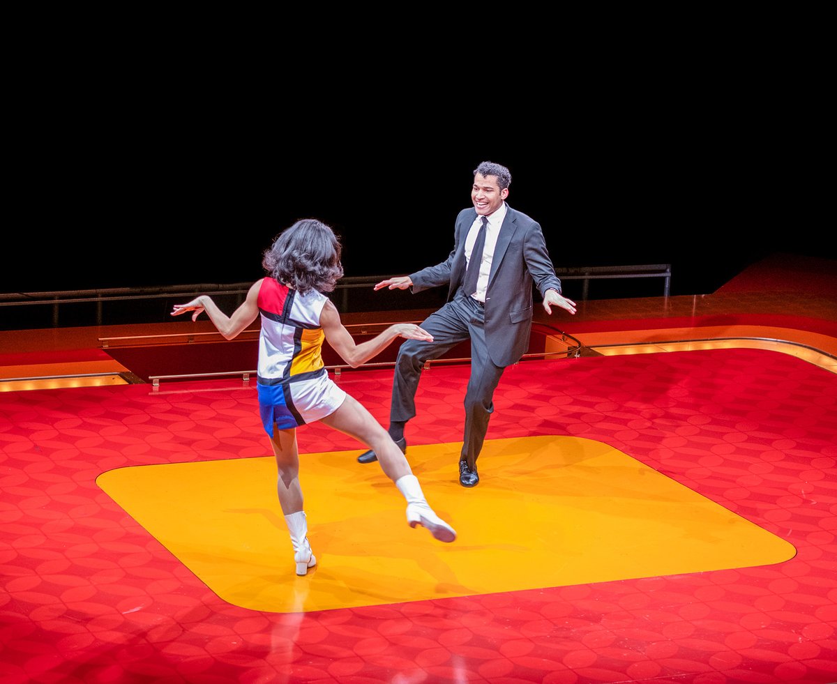 A woman in a Mondrian-inspired shift dress and white go-go boots dances with a man in a suit and tie.