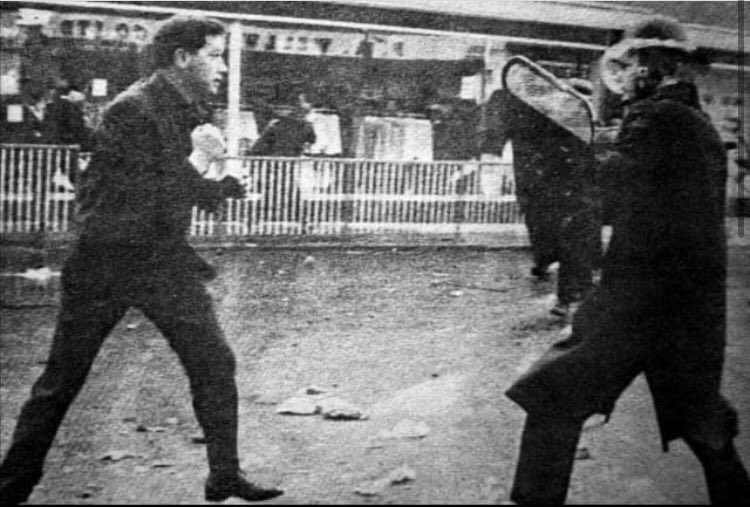 As the RUC open fire on a peaceful protest, Derry boxer, Mickey Deehan, defends the men, women and children running to safety with the only weapons he has on him