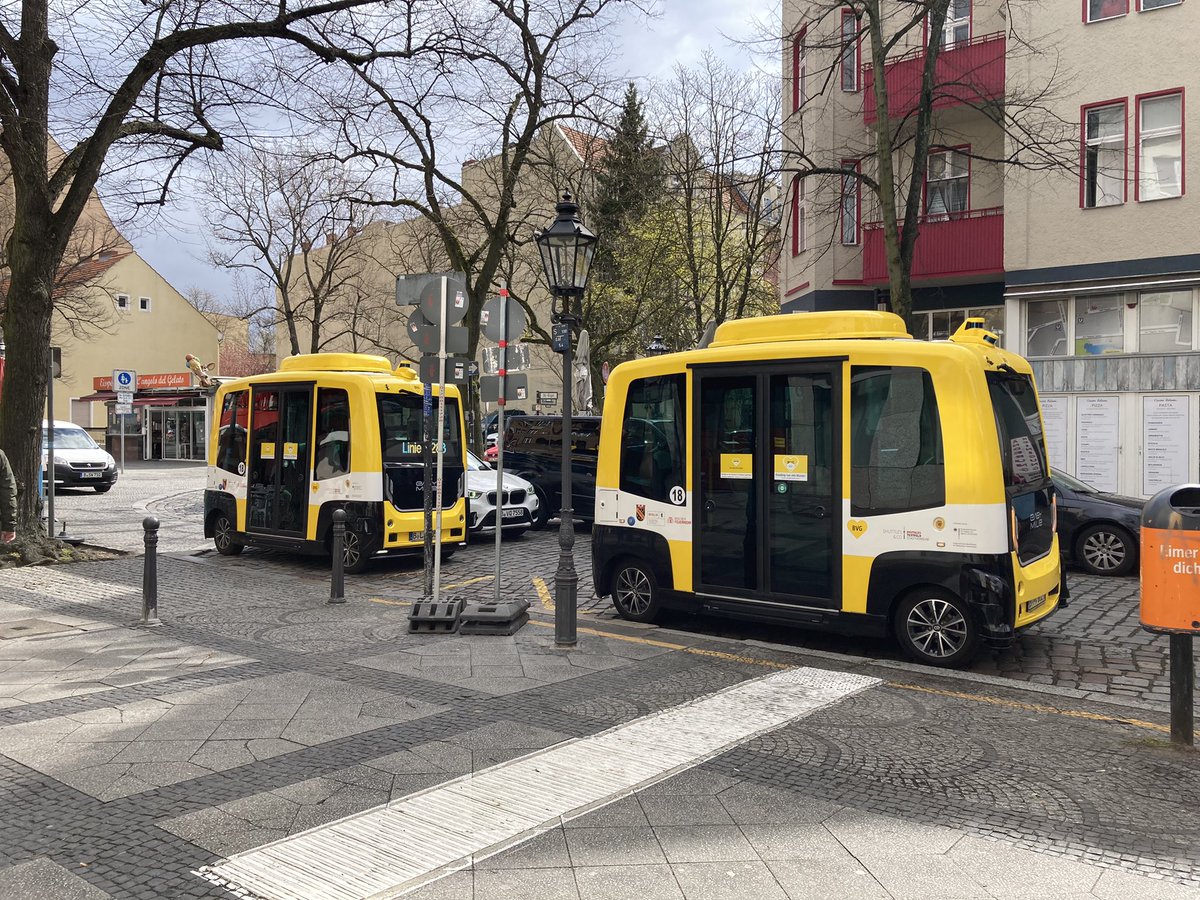Zwei kleine autonom fahrende Busse nebeneinander.