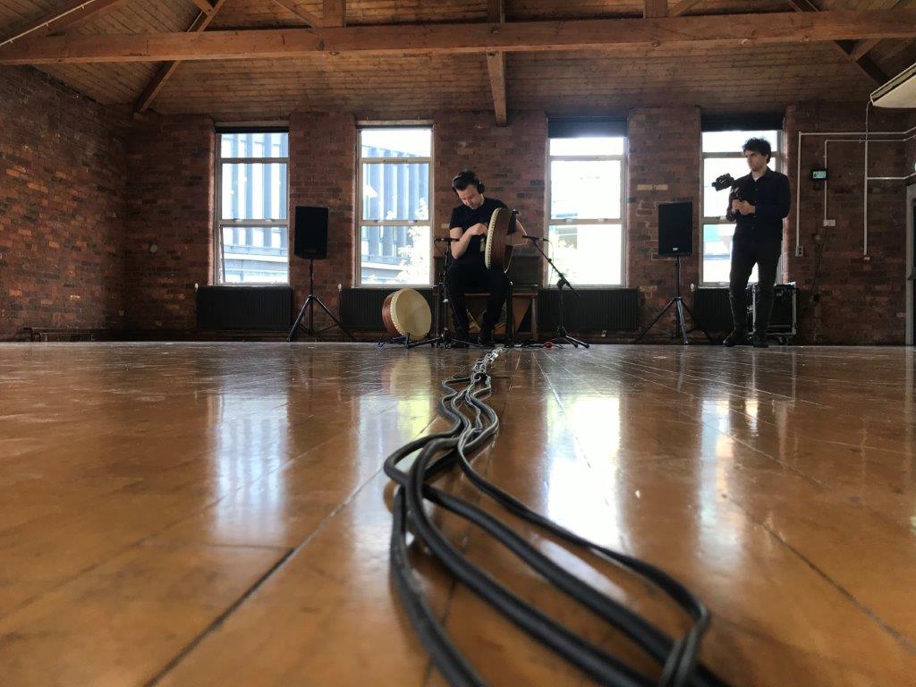 "My research explores solo bodhrán practice. This image was taken during filming of one of my research performances. The visible snake of cables represents how embodied knowledge of the performer can be captured, transmitted and made explicit in arts practice research"