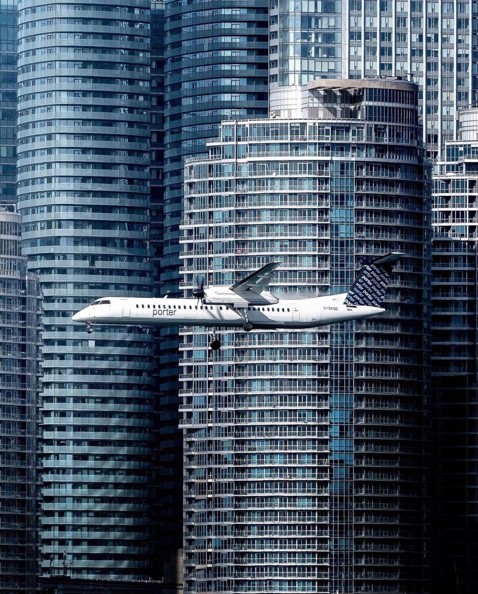 SkiesMag's tweet photo. Wanna play a fun game called, "Find the Q-400"?

here is a @porterairlines Q-400 on final approach for Billy Bishop City Centre Airport amongst a sea of high-rise buildings in Toronto. 

photo credit: @dmairplane
#porterairlines #Q400 https://t.co/gYCevtN3LO