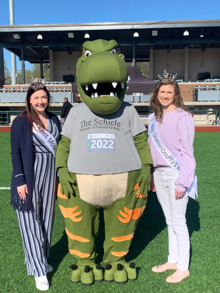 Ever wonder what it is like when beauty queens encounter a dinosaur? That happened at the Community Foundation Run. Miss Mount Holly Andersen Raines and Gaston County’s Outstanding Teen Morgan Wuest got a pic with T. rex, the Schiele Museum’s mascot. Pretty prehistoric, right?