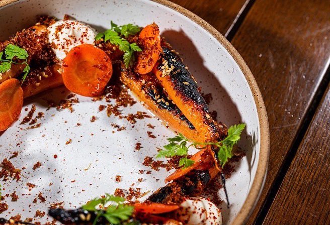 Herbaceous, ember-roasted carrots with creamy ricotta, drizzled with smoked honey and sprinkled with chili crunch.