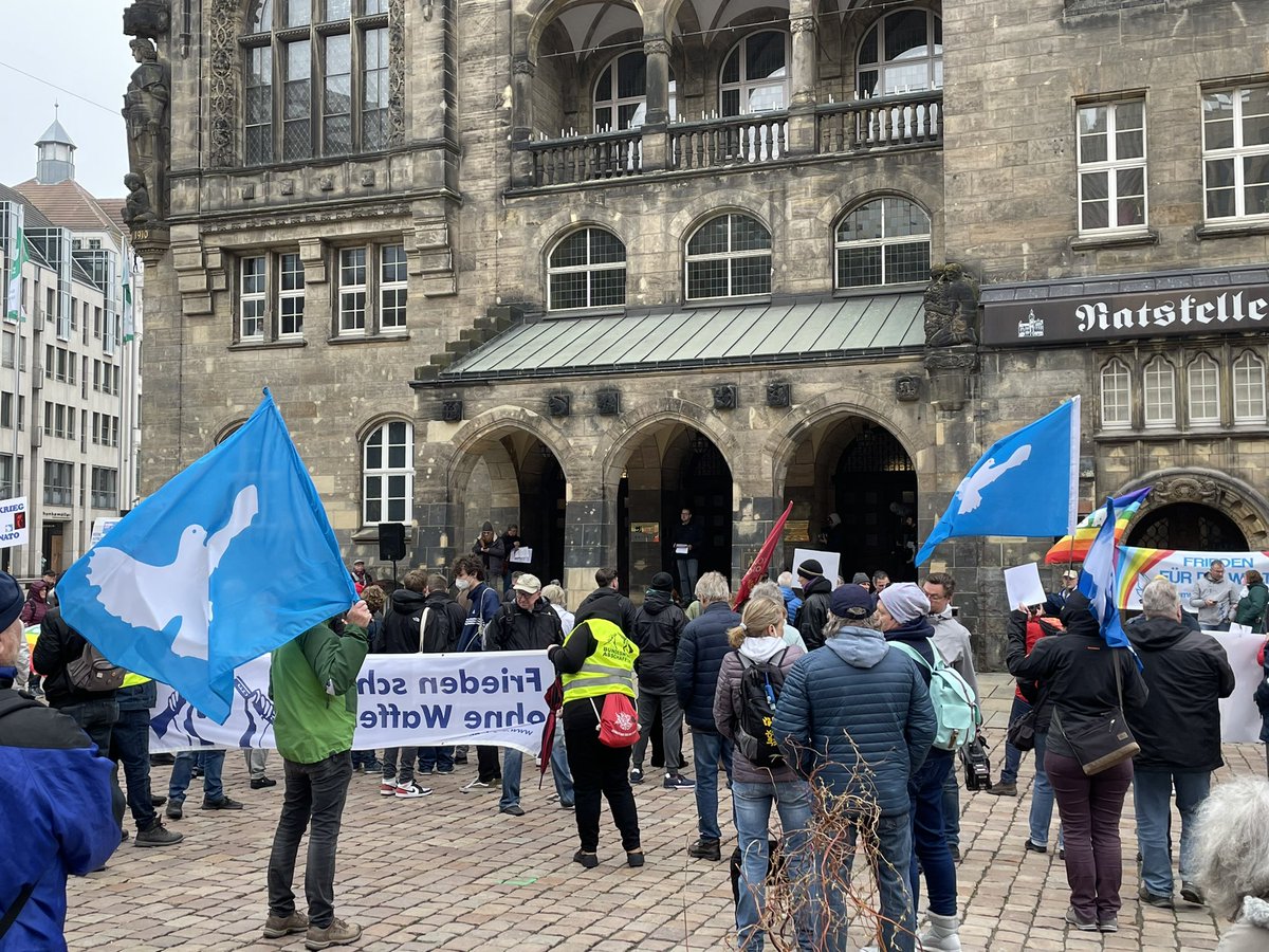 Menschen vorm Rathaus Chemnitz mit blauen Fahnen und einer Friedenstaube drauf