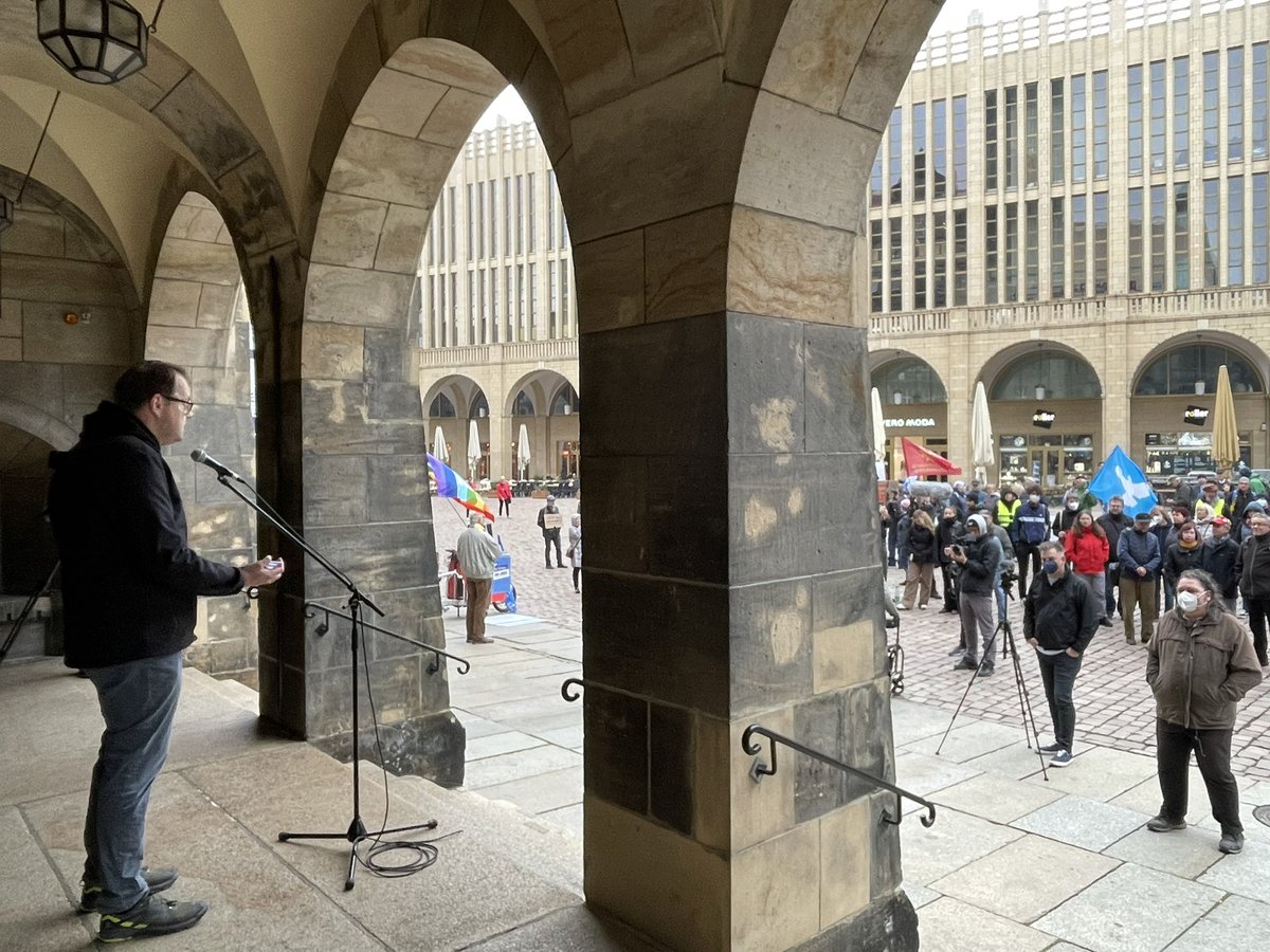 Sören Pellmann am Mikrofon. Im Bild zwei Torbögen. Rechts Demoteilnehmer