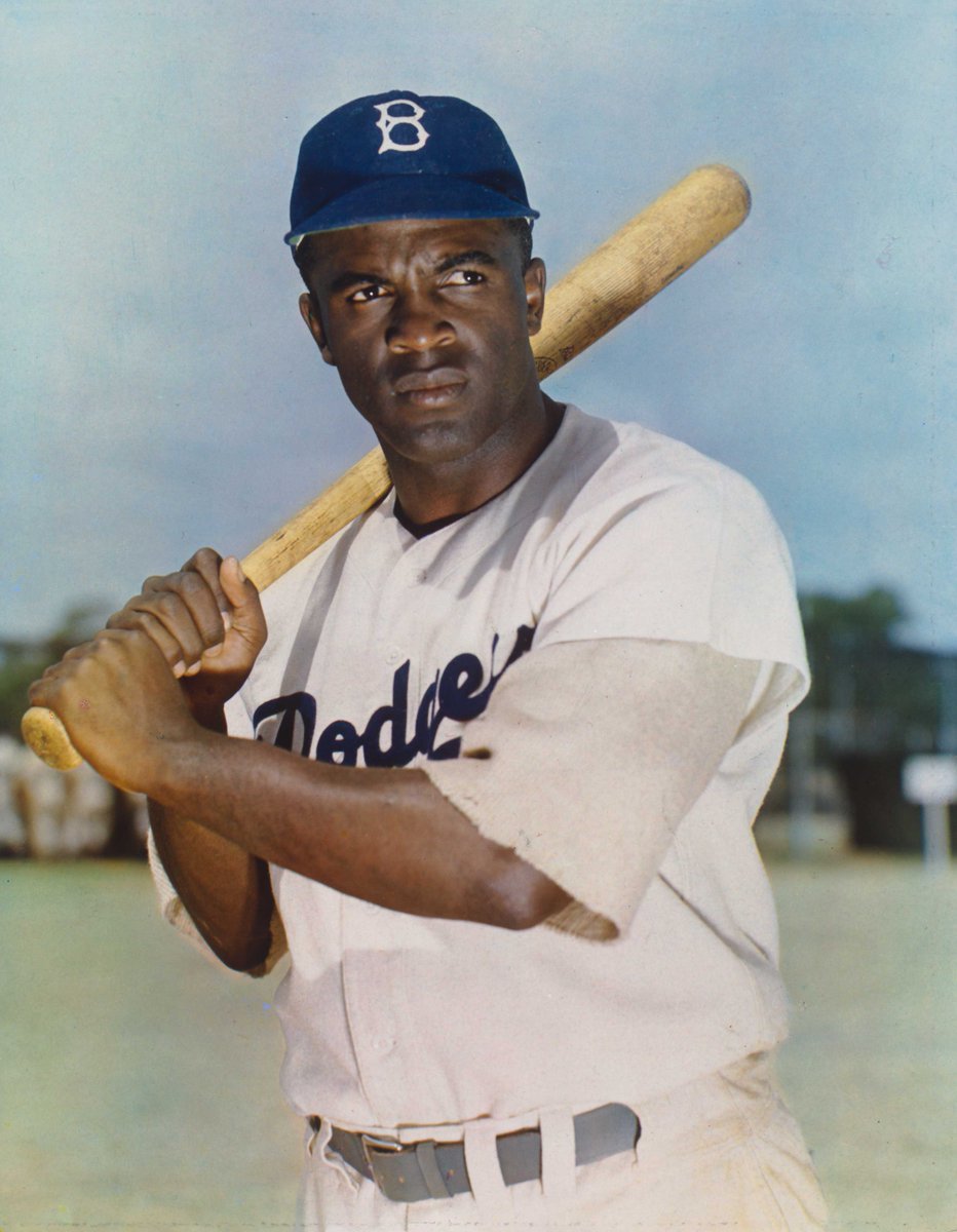 Jackie Robinson wearing a Brooklyn Dodgers uniform and holding a baseball bat