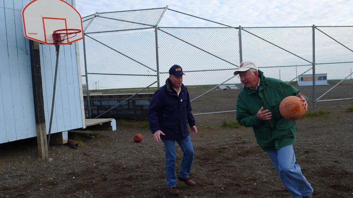 ANC_Historian's tweet photo. Aug 12, 2012, Ken Salazar (green coat), Secretary of Interior under President Obama, playing basketball against unidentified man at Nuiqsut. Via National Archives #alaskahistory #nuiqsut https://t.co/Kkx0Yn42im