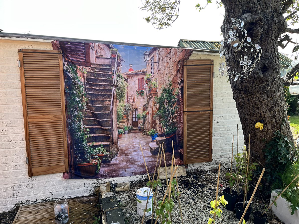 Tooks007's tweet photo. Old garage wall into a feature wall, made with a shower curtain, a tin of paint & some old shutters ๐#easterproject #GardeningTwitter https://t.co/XhjG6Wv8dy