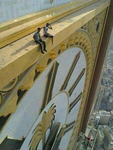 Two people sitting on the Abraj Al Bait clock tower in mecca