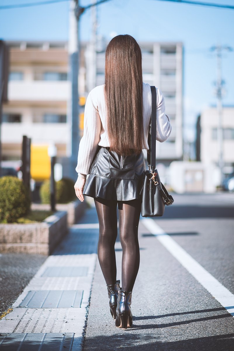 フェイクレザーのミニスカートに光沢黒ストッキングとショートブーツの
