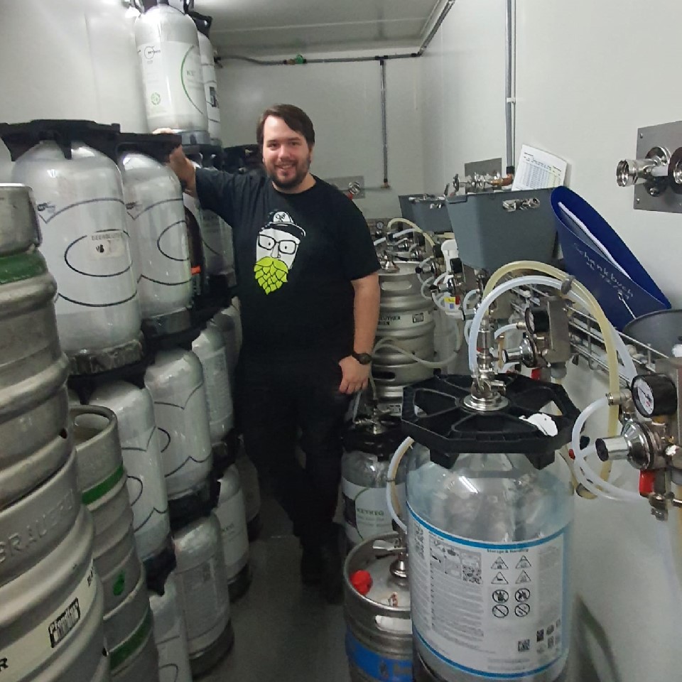 Bar staff standing in a walk-in cooler surrounded by beer kegs.