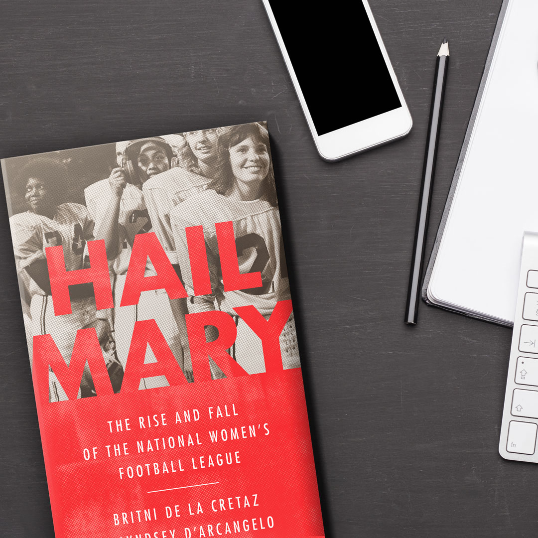 A copy of the book HAIL MARY by Britni de la Cretaz
and Lyndsey D’Arcangelo on a charcoal grey table. next to a smart phone, keyboard, laptop and black pencil. 