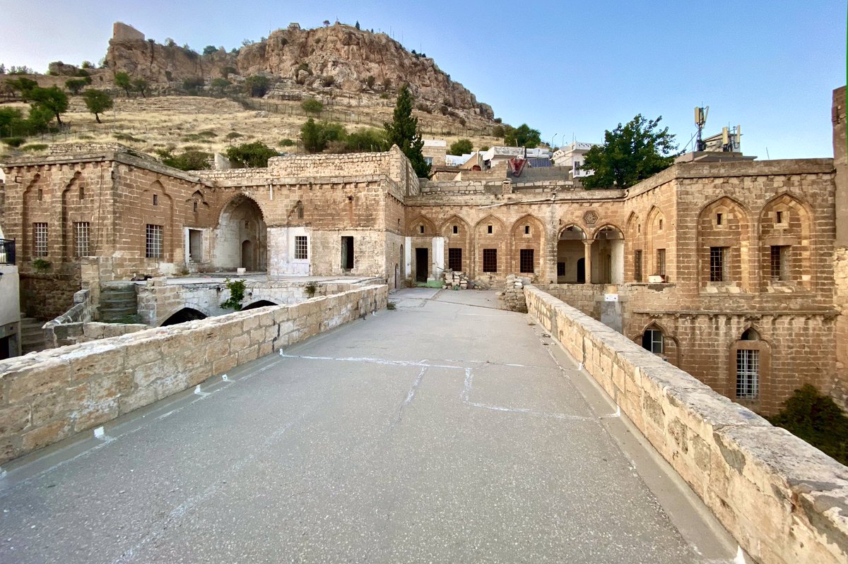 5. Mardin Bienali mekanlarını keşfetmeye devam ediyoruz.

📍 #DeveliHan 

Mezopotamya ovasına hakim, Mardin Kalesinin hemen altında, Gül Mahallesi’nde geleneksel Mardin mimari konaklarının önemli örneklerinden biridir. Tarihçesi ile ilgili, herhangi bir kitabeye ve tarihe