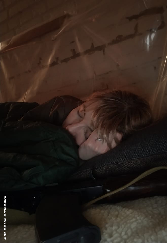 Olena Bilozerska liegt dick eingepackt in einem Luftschutzbunker. Unter ihrem Kissen liegt eine Waffe.