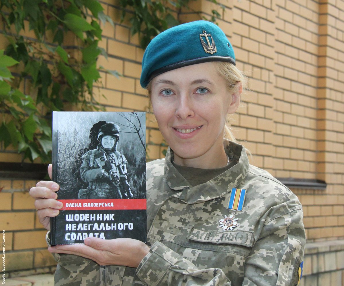 Olena Bilozerska präsentiert ihr Buch über ihre Kriegserfahrungen. Sie trägt Militärkleidung und ein blaues Barett. Sie hat einen Orden am Revers.