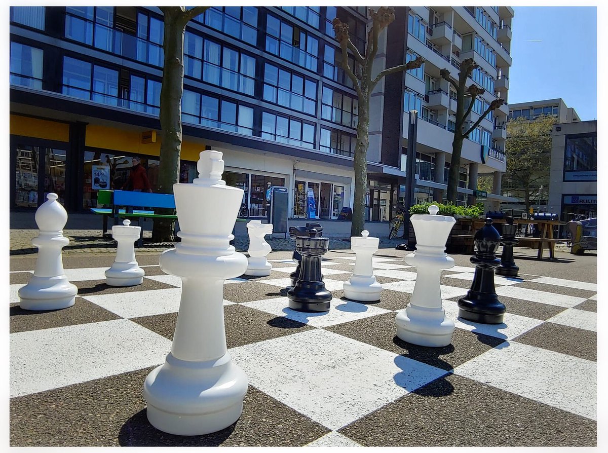 Schaak! Levensgrote schaakmat*, voor onze deur. Ook op de stadstuin-tafel wordt geschaakt. Nu zondag 24 april is om 14u de feestelijke ingebruikname (tot 17u).
Wethouder Jordy Clemens verricht de eerste (openings-)zet. Haal de stukken (voortaan) bij ons!