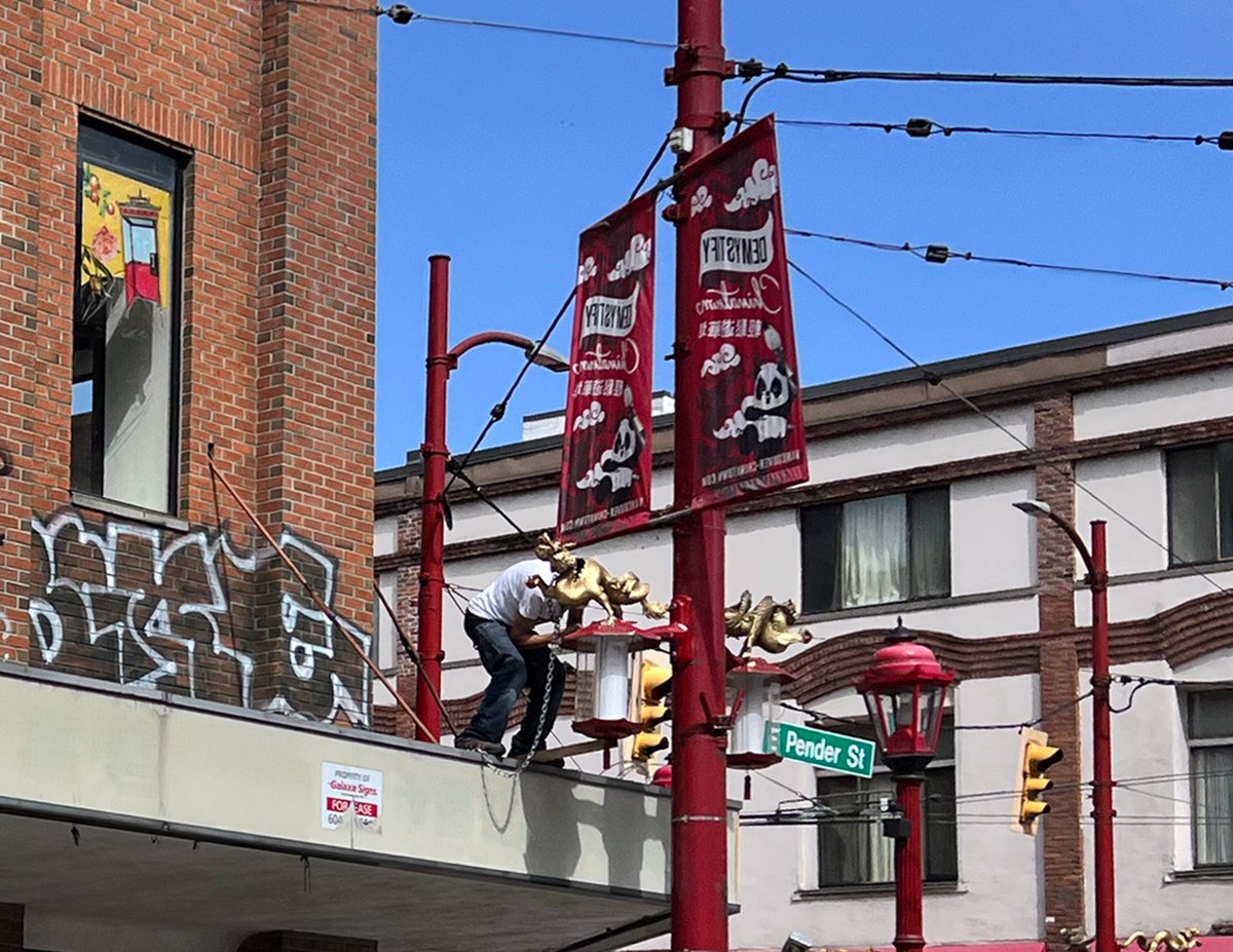 ShotsByFox's tweet photo. If Chinatown were a film set; meet your grips. One man uses weed-blower to cover sound of his friend’s hacksaw in attempt to remove dragon streetlamp. Broad daylight Sunday afternoon @cityofvancouver 

#vancouverpolice #chinatownyvr #dragons https://t.co/W3mJyrco2o