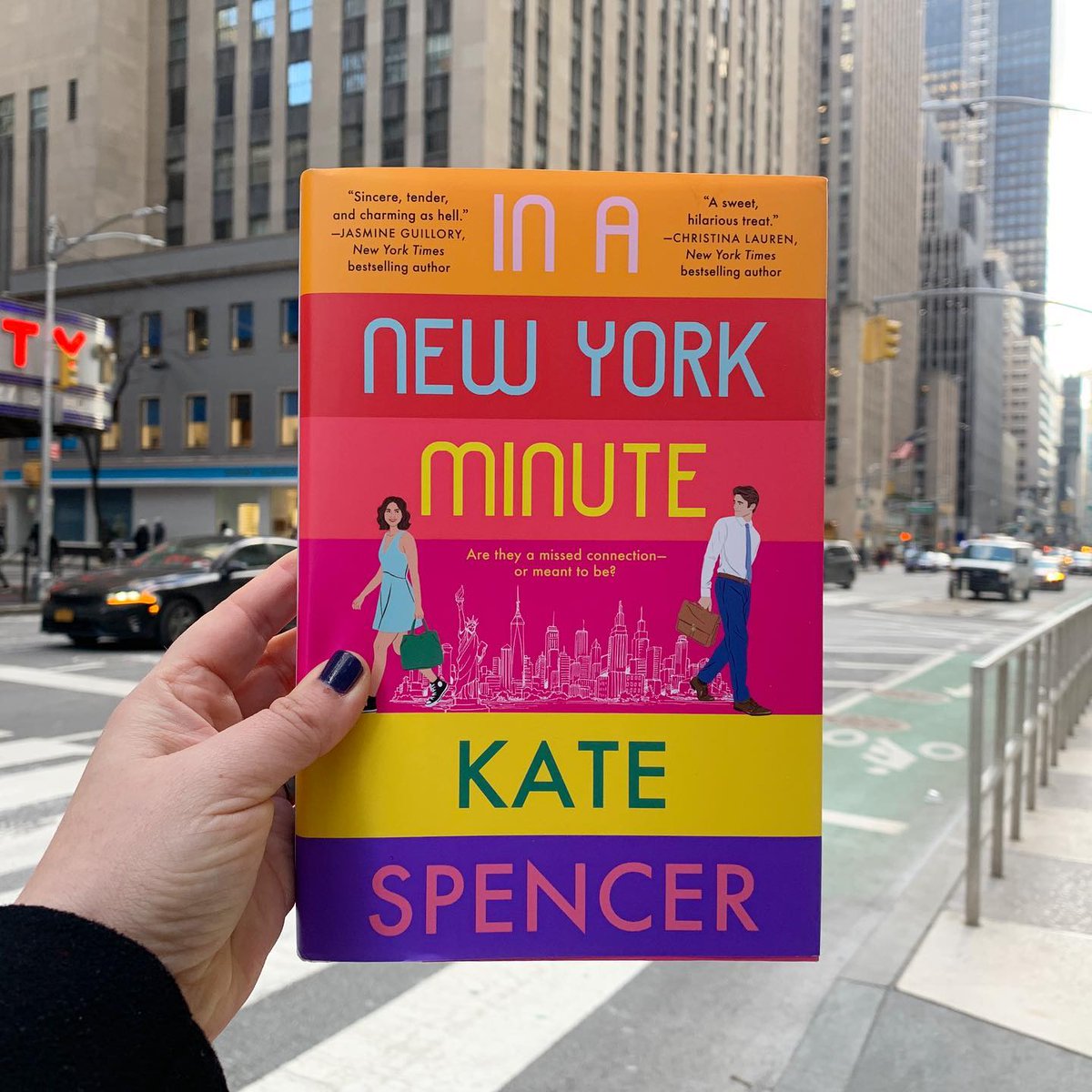 IN A NEW YORK MINUTE by Kate Spencer with a view of new york city street and building in the background.