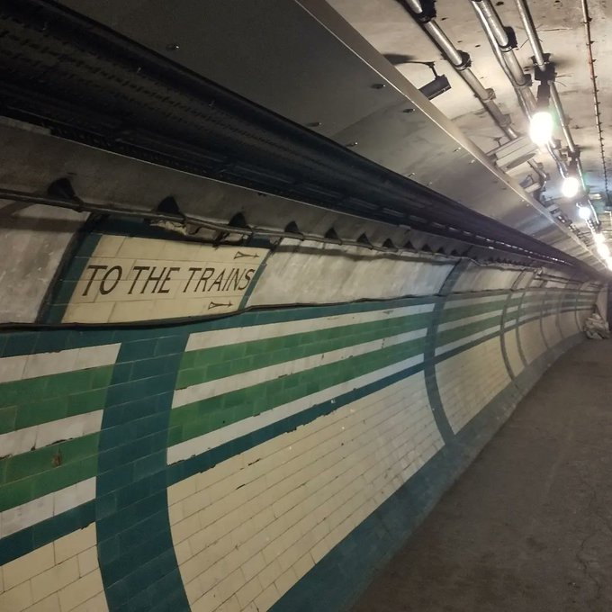 Piccadilly Circus non public areas still have the original tiling like these green and blue examples that can be seen running along the tunnel walls. There's a sign that says 'To The Trains'.